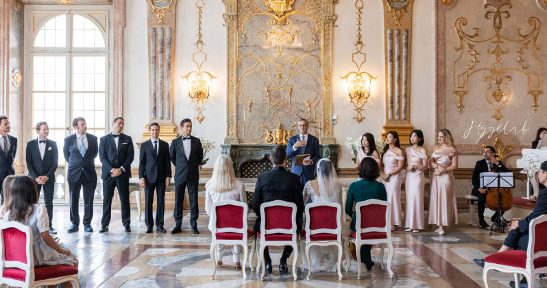 Toàn cảnh buổi lễ cưới của cặp đôi và phù dâu trong một khán phòng Baroque trang trí công phu với vàng và đá cẩm thạch tại Cung điện Mirabell, Salzburg.